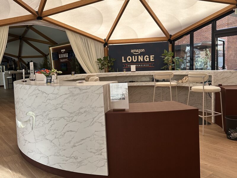 Curved white and brown reception counter inside an Amazon event lounge