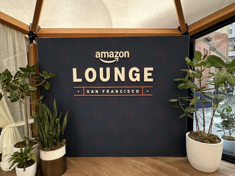 Black event lounge wall with illuminated lettering and potted plants
