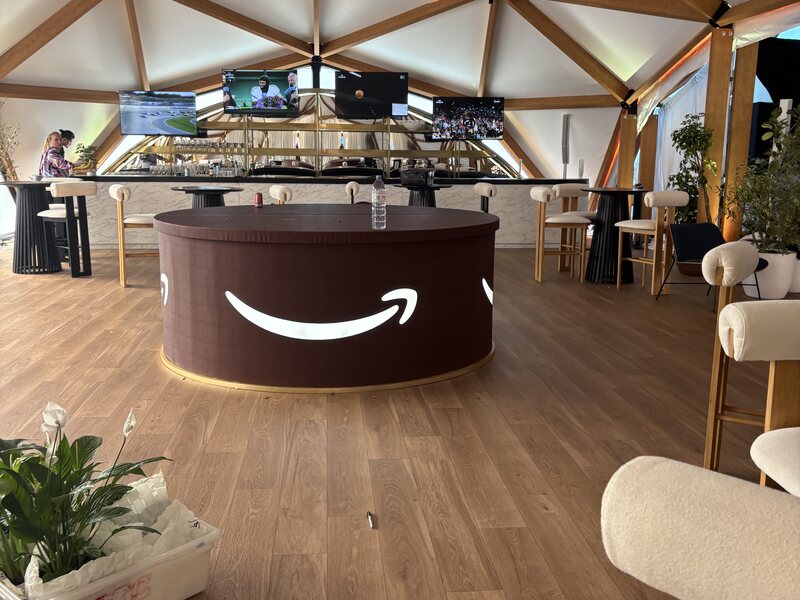 Round branded reception counter inside a furnished event lounge