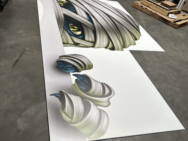Large eye and hair illustrations printed across sheets on the production floor