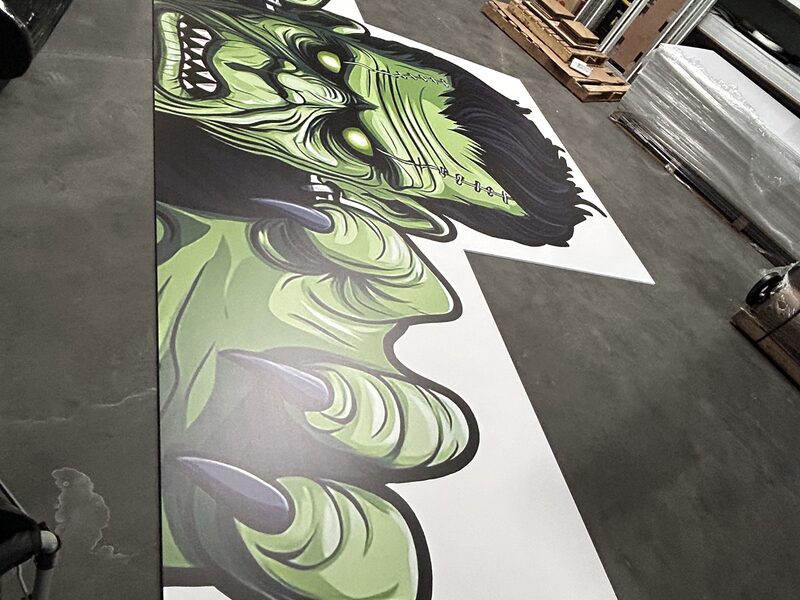 Large green illustrated graphic printed on a sheet on the production floor