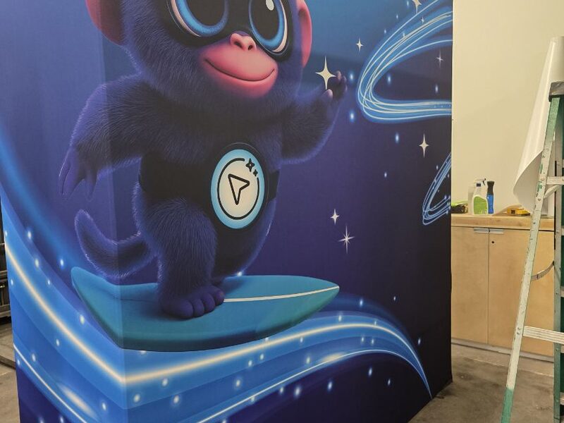 Tall printed event panel with a blue cartoon character on a futuristic blue background