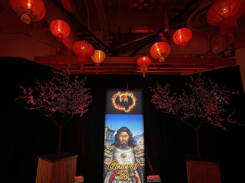 Glowing illustrated display tower beneath red lanterns in a dark event room