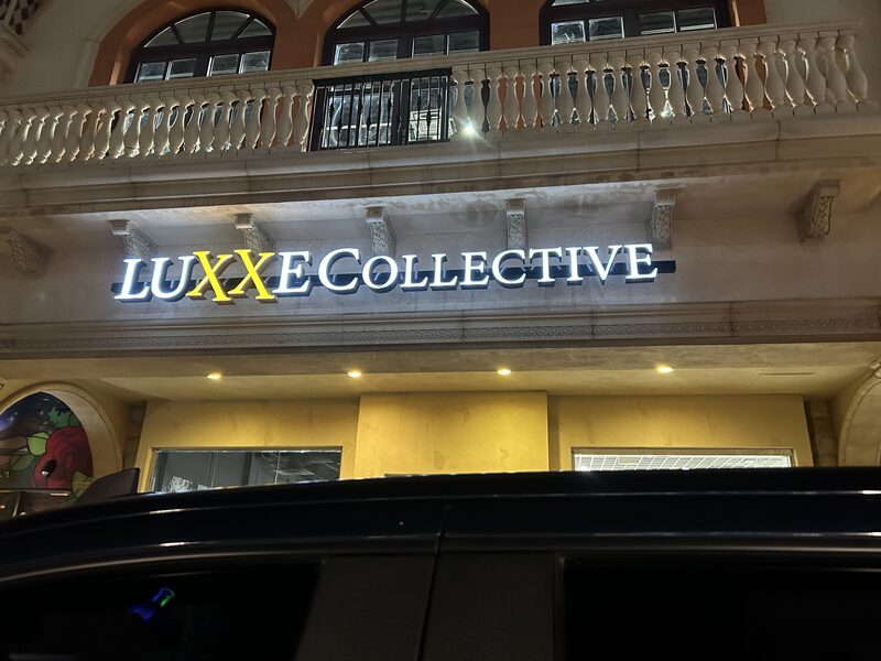 Illuminated Luxxe Collective lettering mounted above a storefront entrance