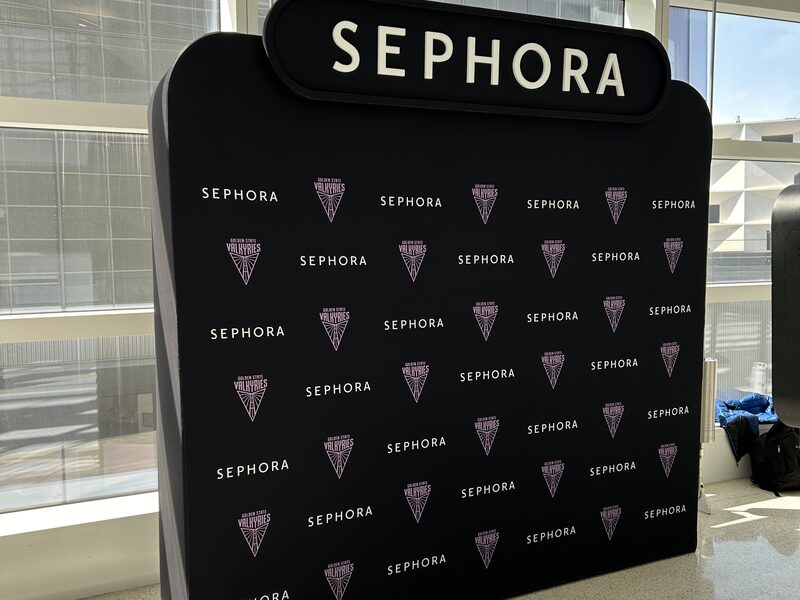 Freestanding black Sephora step-and-repeat photo backdrop beside glass windows