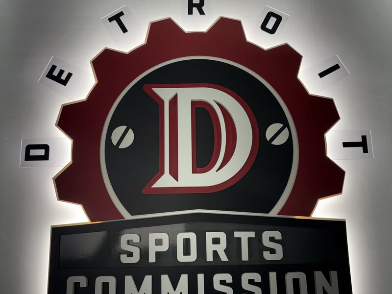 Illuminated Detroit Sports Commission wall sign with a gear-shaped logo