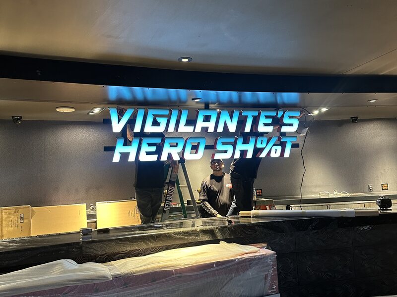 Illuminated Vigilante’s Hero Shot lettering above a service counter