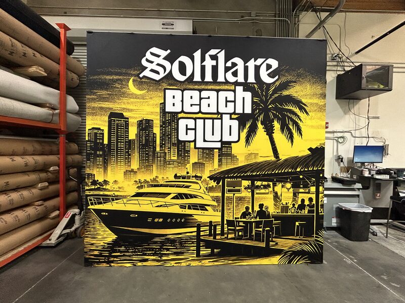 Black-and-yellow Solflare Beach Club display with tropical graphics and seating