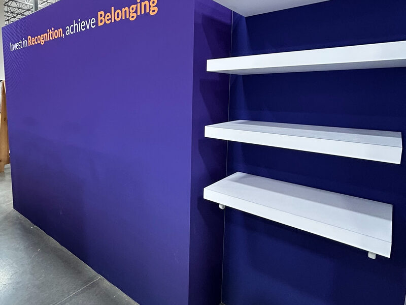 Purple exhibit wall with printed lettering and white display shelves