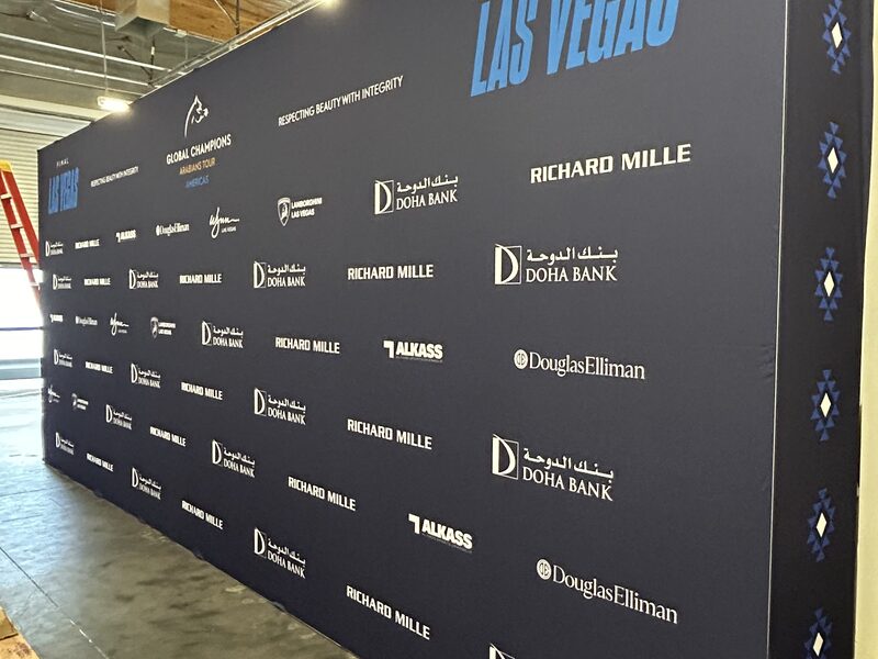 Floor-to-ceiling step-and-repeat logo wall installed at a trade show
