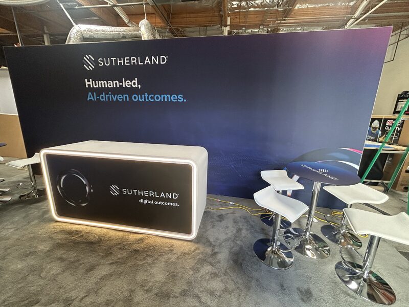 Trade show booth with a curved printed header and coordinated blue exhibit graphics