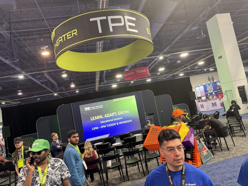 Circular TPE hanging sign above a presentation area on a busy trade show floor