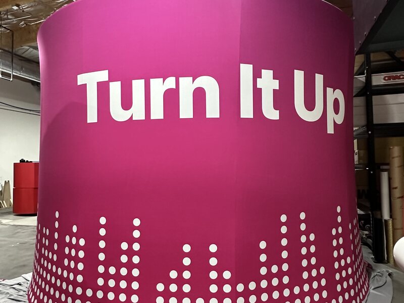 Curved magenta Turn It Up trade show counter with white graphics