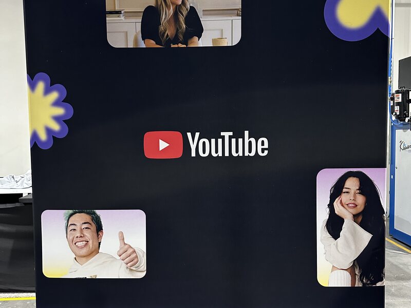 Black YouTube exhibit wall with colorful graphics and portrait screens